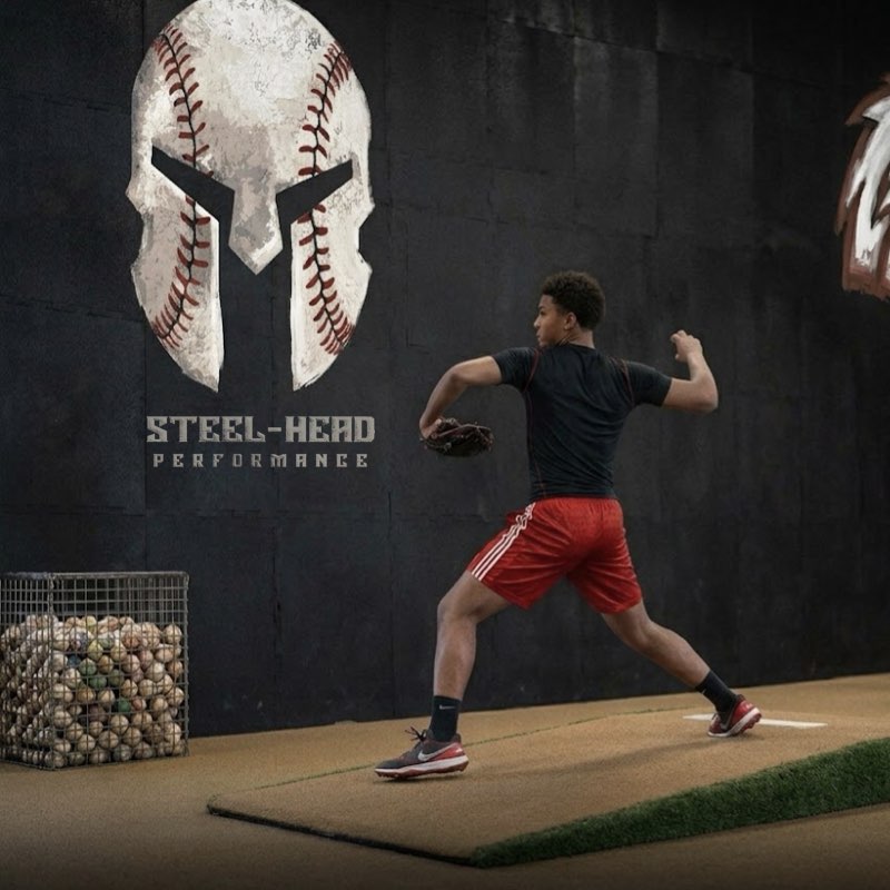 Pitcher driving through his delivery in front of the Steel-Head wall